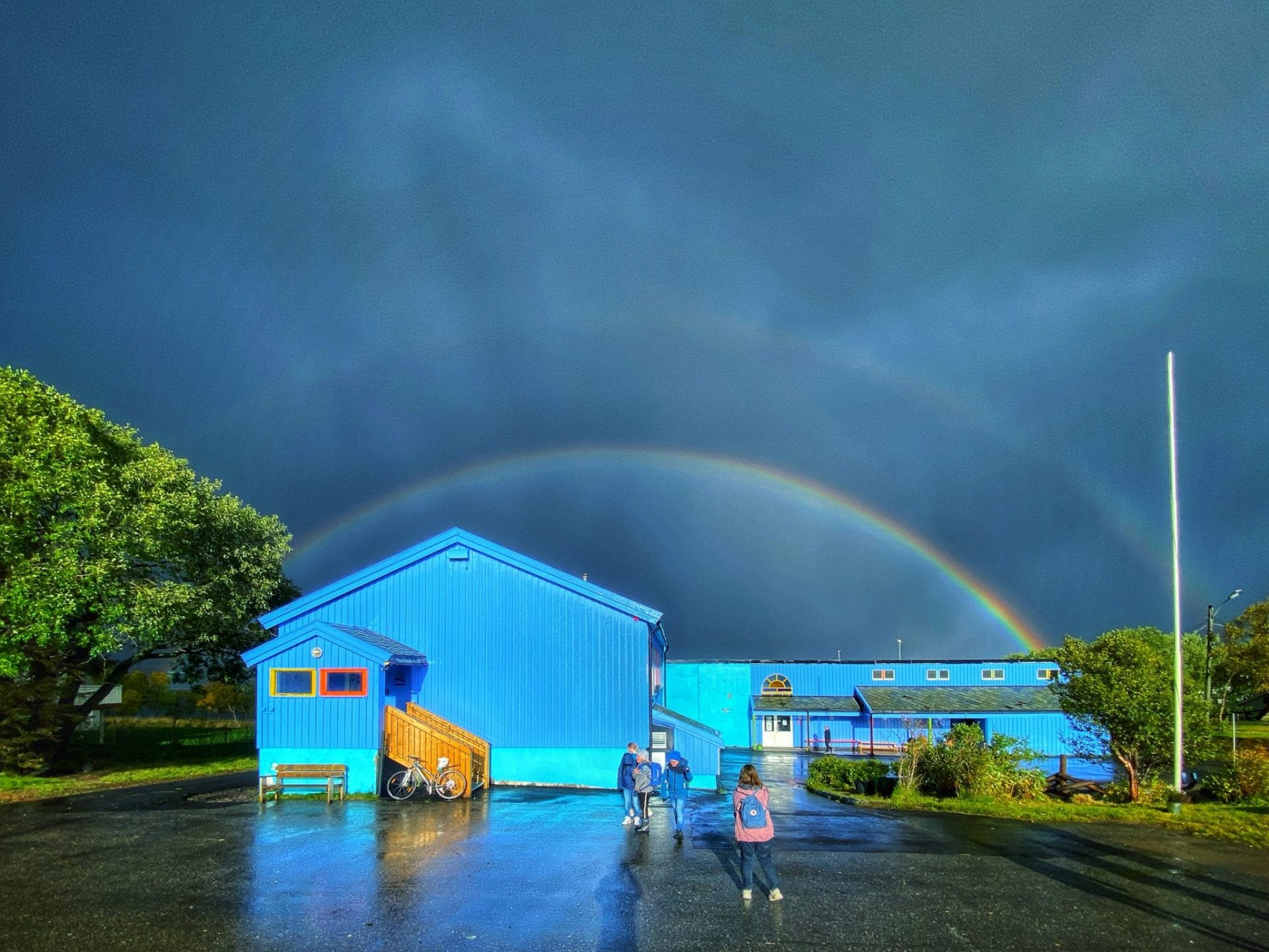 Blå skole med regnbuen i bakgrunn
